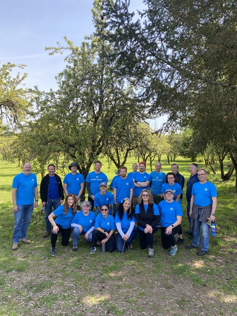 HP Volunteers at Foley  20 volunteers in blue HP shirts in front of a pear orchard